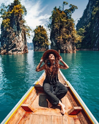 Traveller relaxing on a long-tail boat surrounded by tropical limestone islands