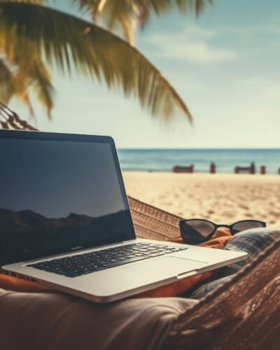 Person working remotely on a laptop in a hammock on a tropical beach during a longer stay trip.